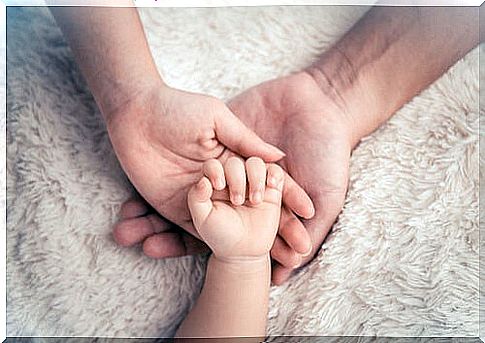 Baby's hand over a mother's hand to represent the bond of attachment