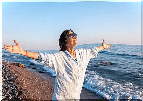 Senior woman with open arms on the beach