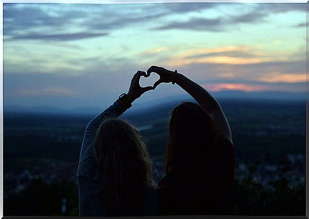 Friends forming a heart with their hands symbolizing the theories of Robert Cialdini