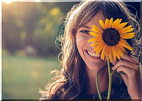 Woman with a smile and a sunflower in her hand symbolizing the theories of Robert Cialdini