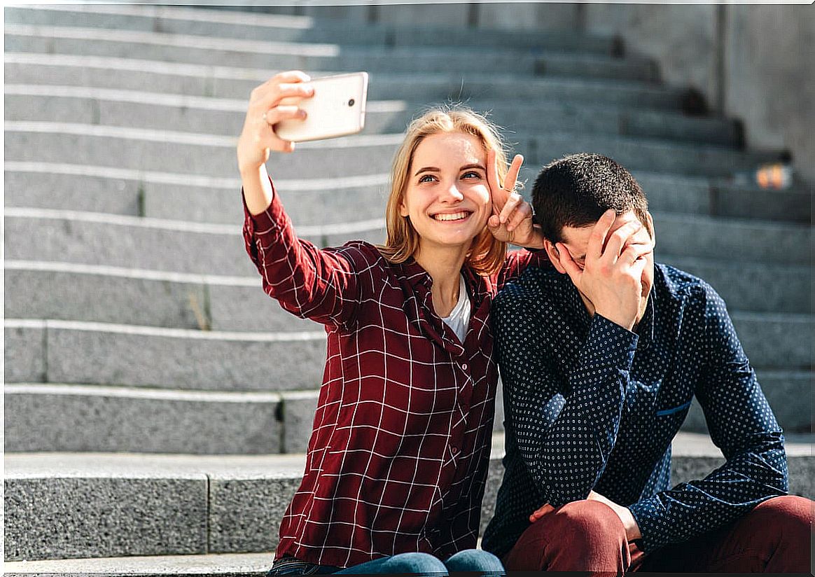 Girl taking a selfie while her boyfriend doesn't want to